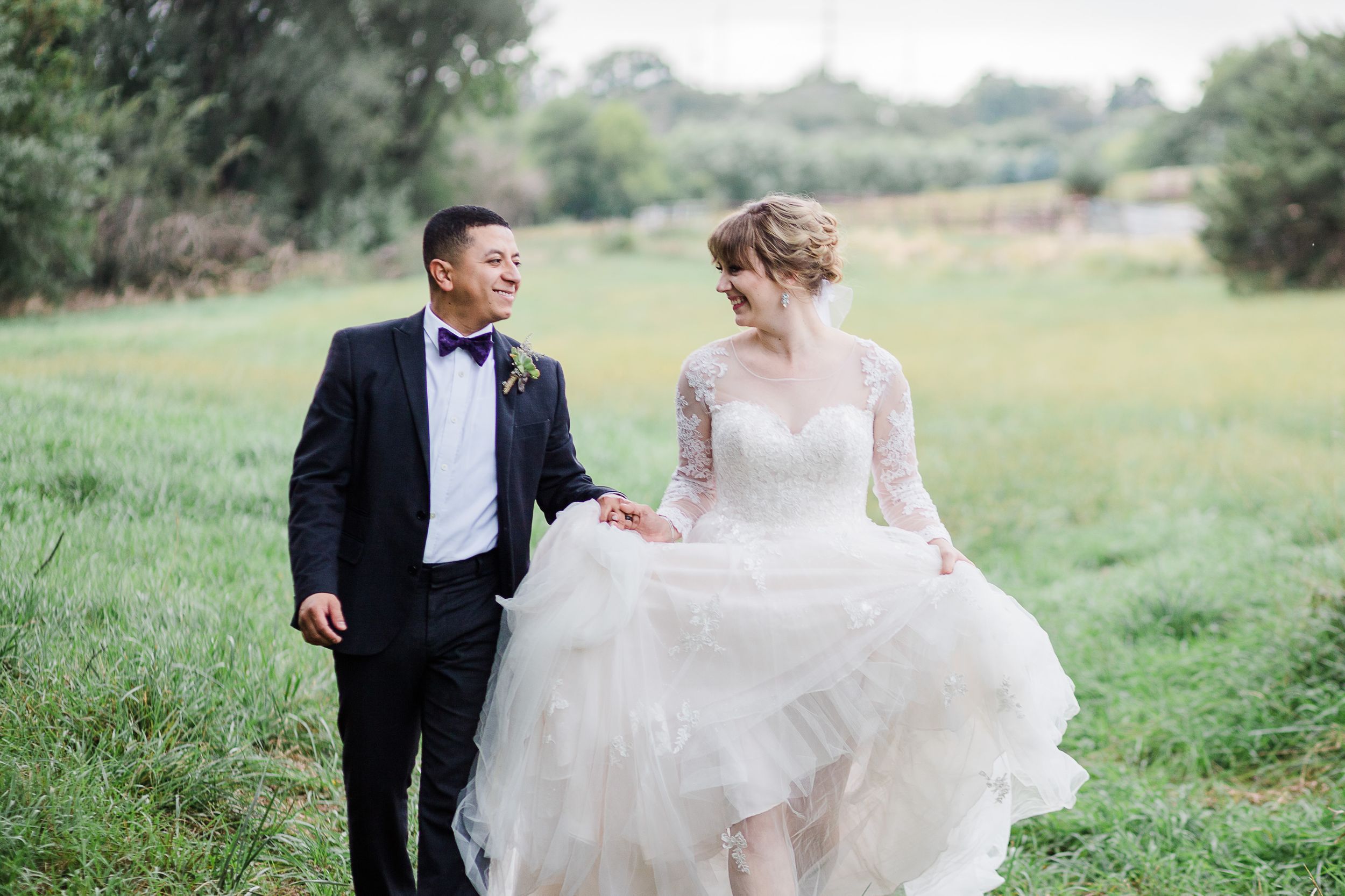 Bride and groom walking through a field by Hudson Valley photographer