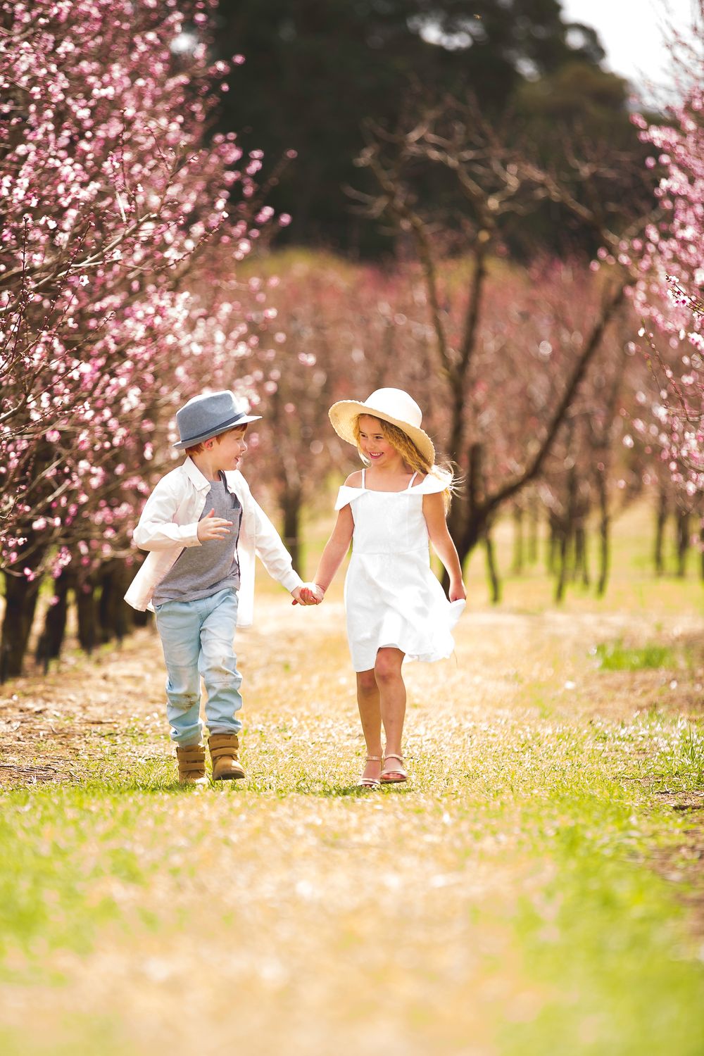 family photography girl and boy holding hands walking in orchard