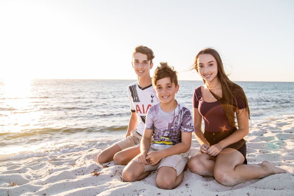 family photography three kids sitting on beach in the sun
