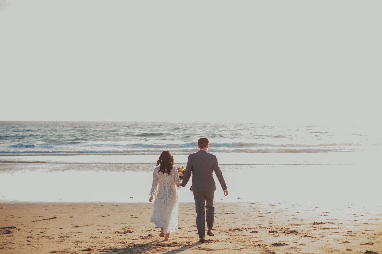 bride & groom walking towards ocean
