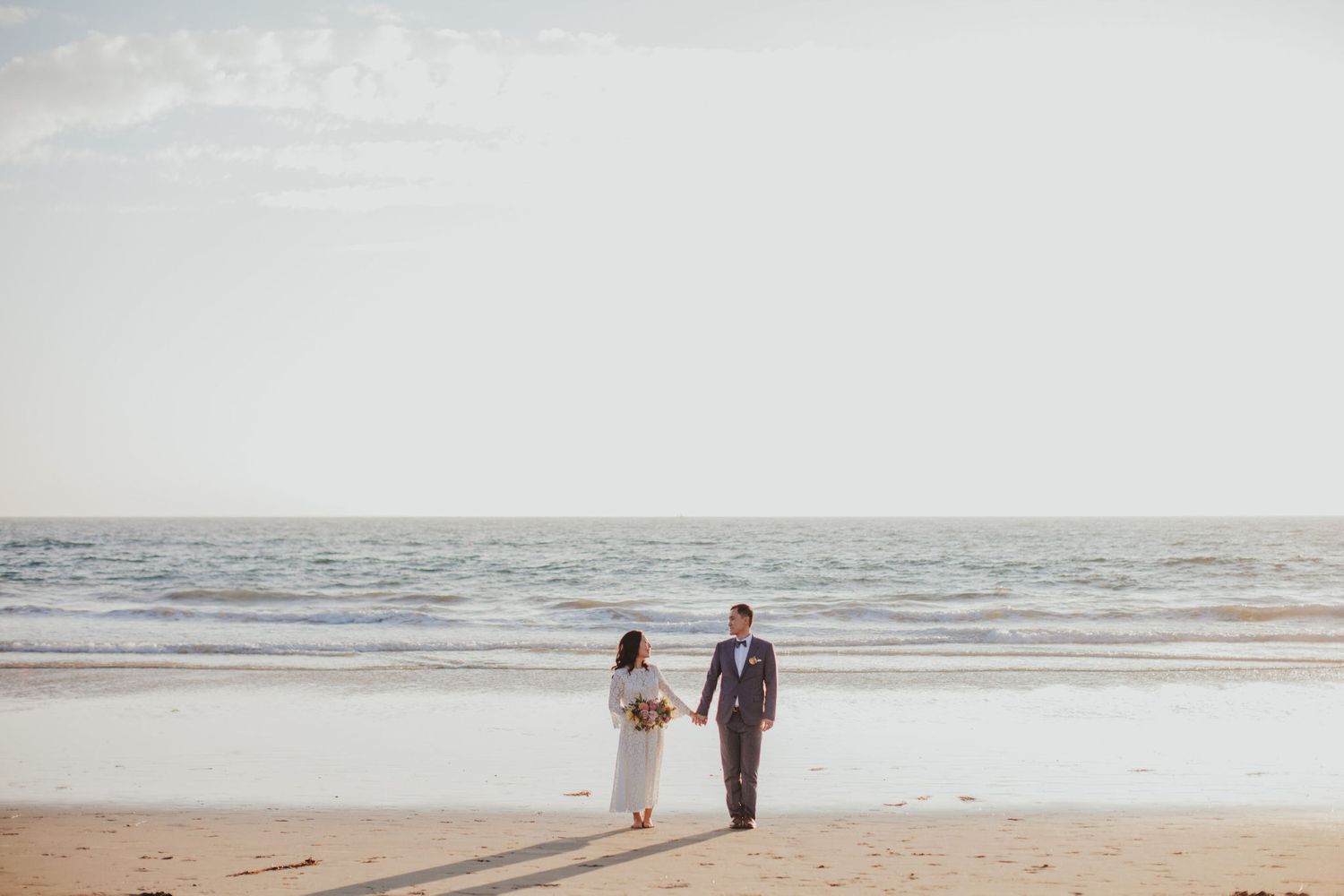 bride & groom walking away from ocean