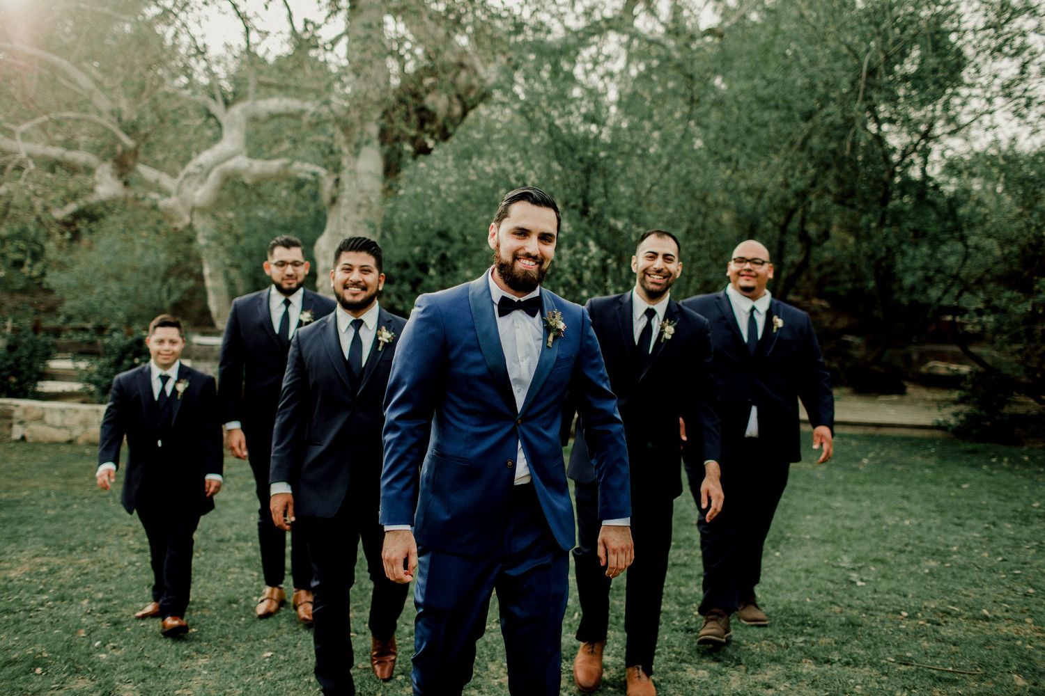 groom and wedding party walking in field