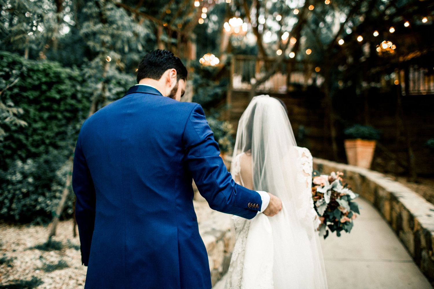 groom helping bride with dress and veil