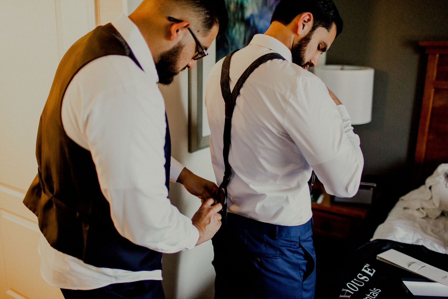 best man helping groom with suspenders at holiday inn
