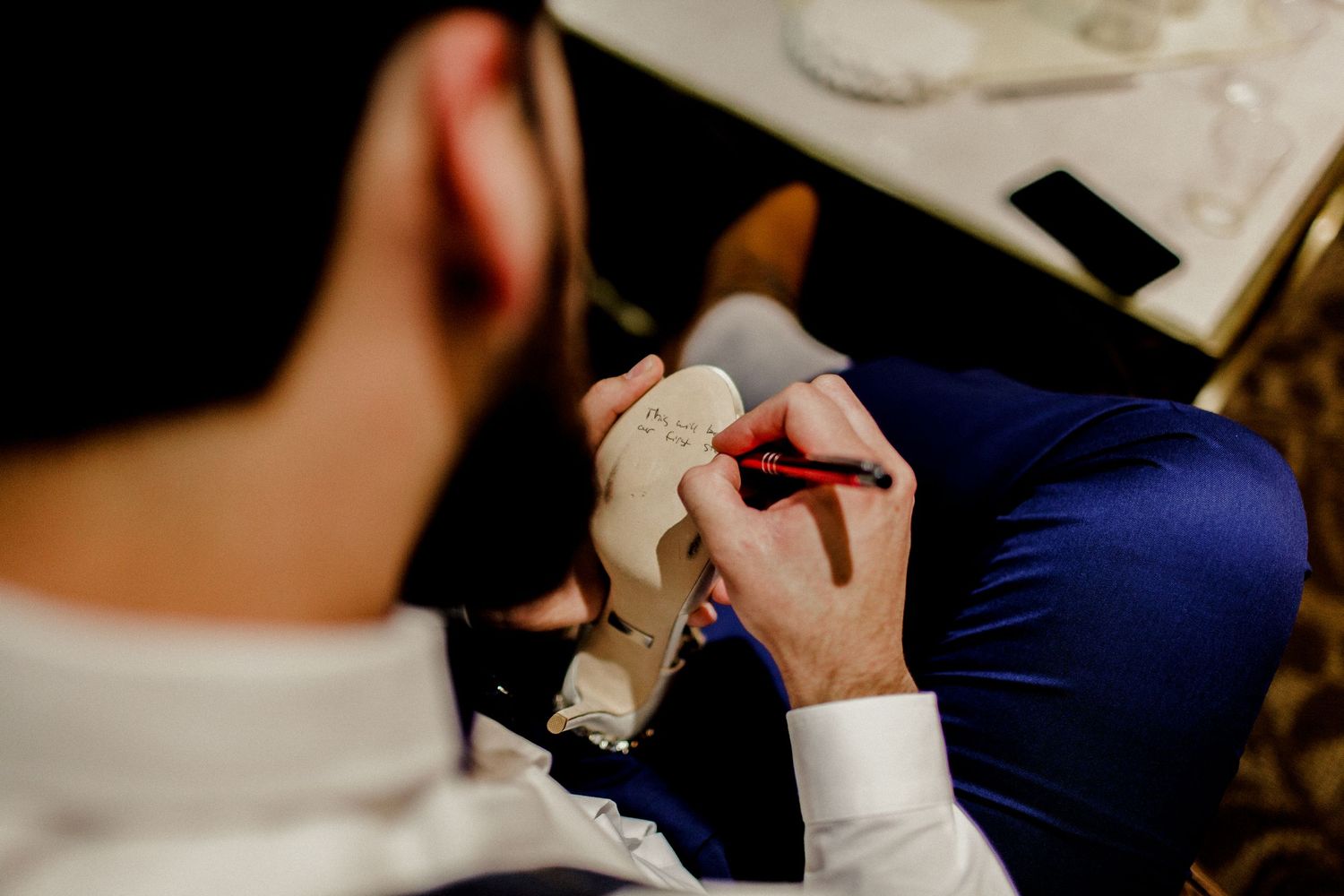 groom writing message on shoe for bride