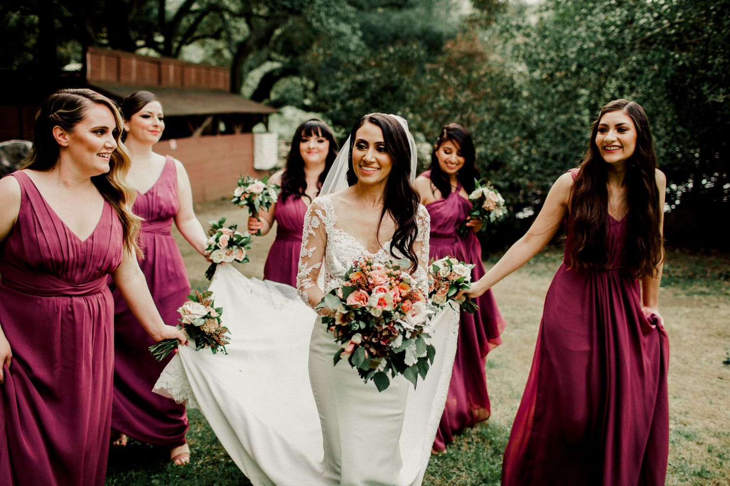 bridesmaids walking with bride helping with dress