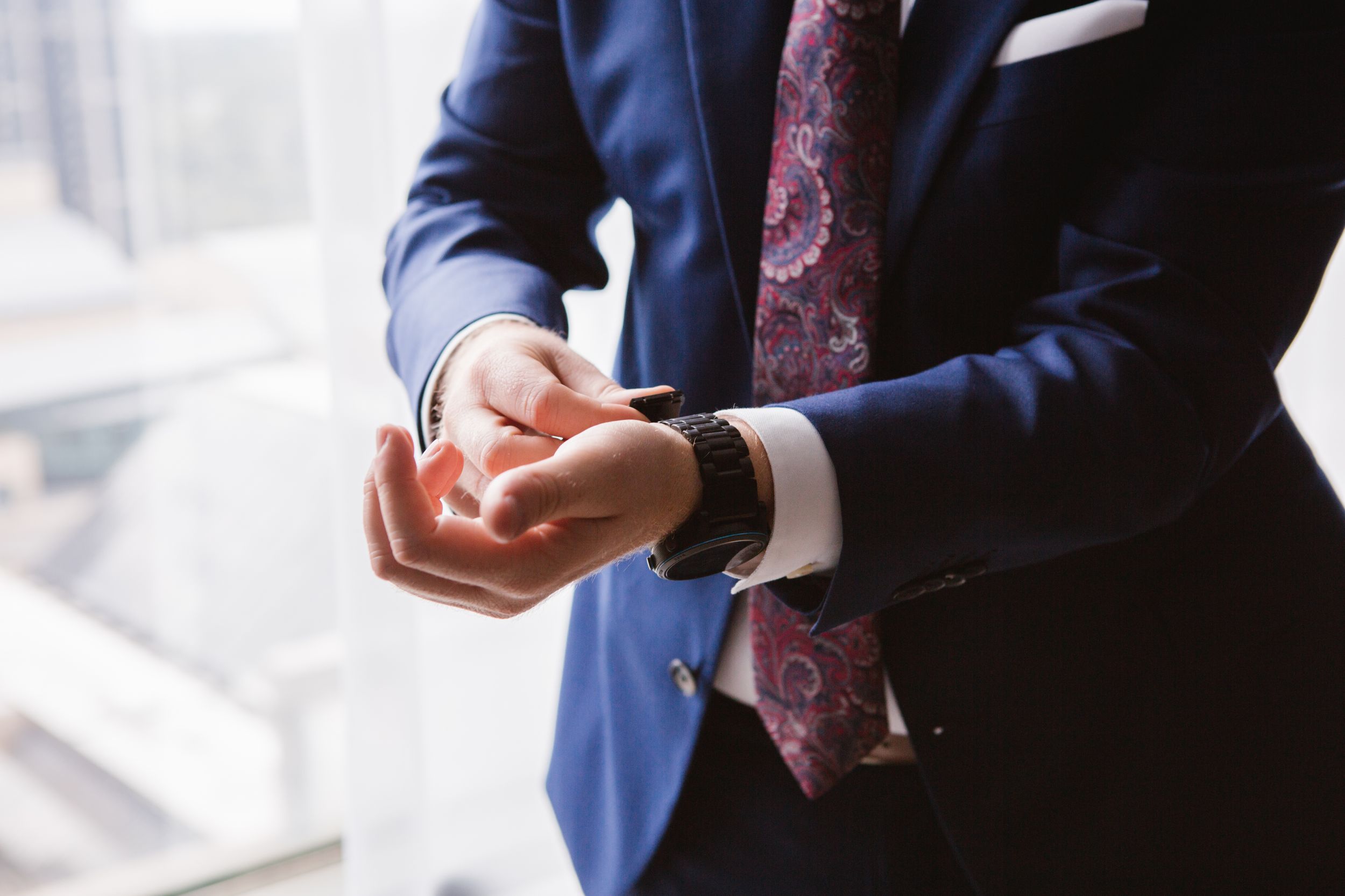 groom putting on his watch against city skyline