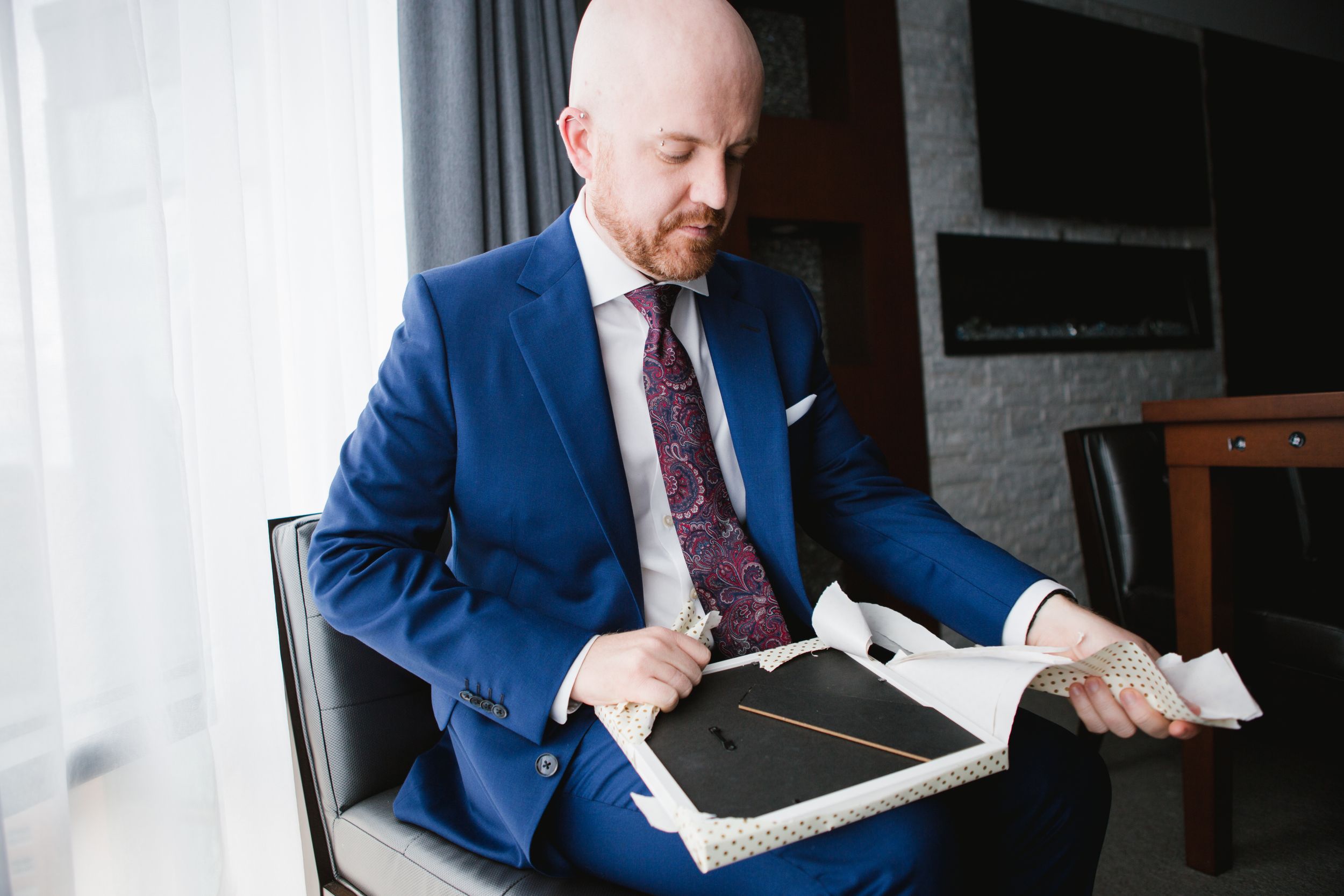 groom in blue suit opening his gift