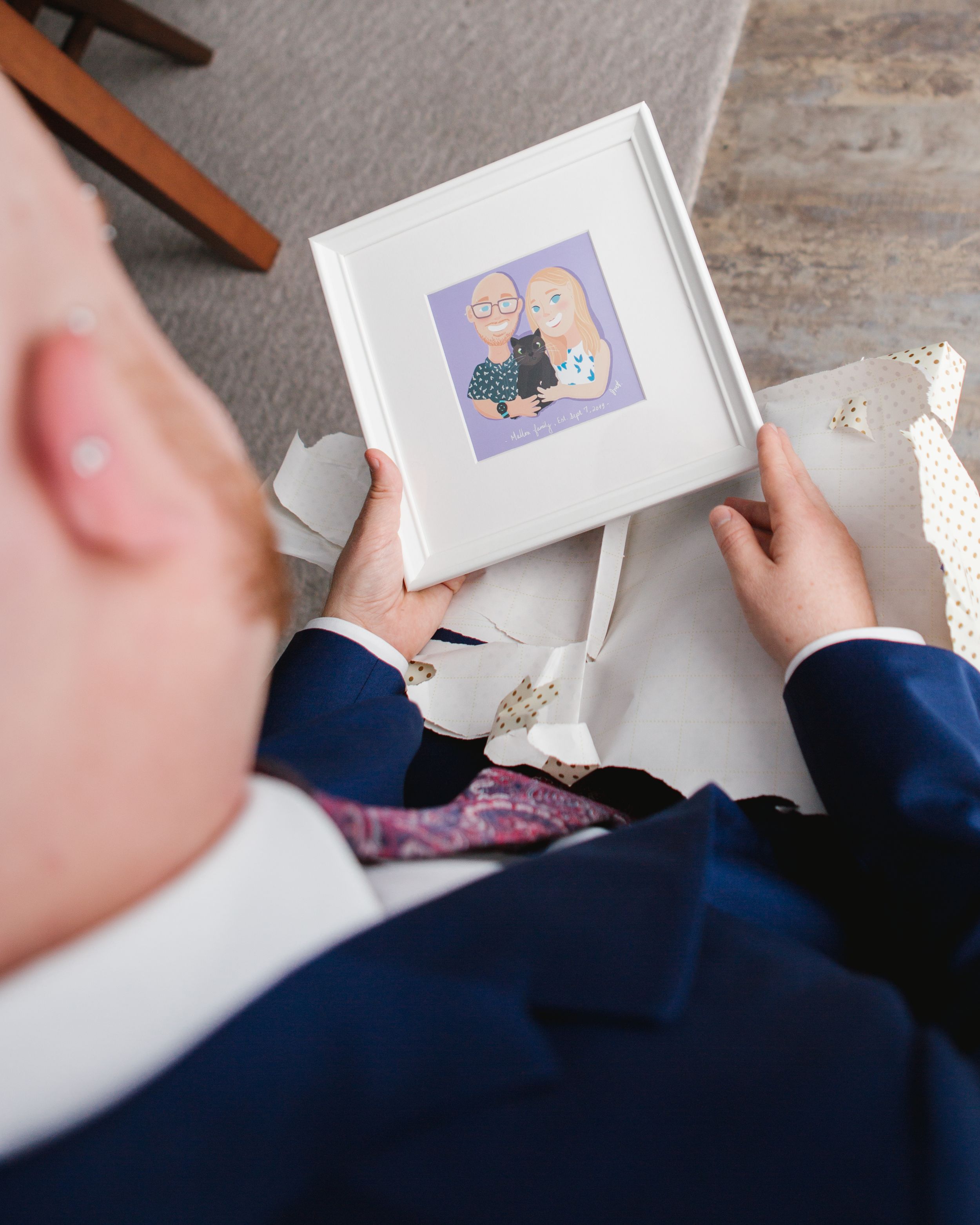 groom looking at a cartoon portrait of him and his fiance