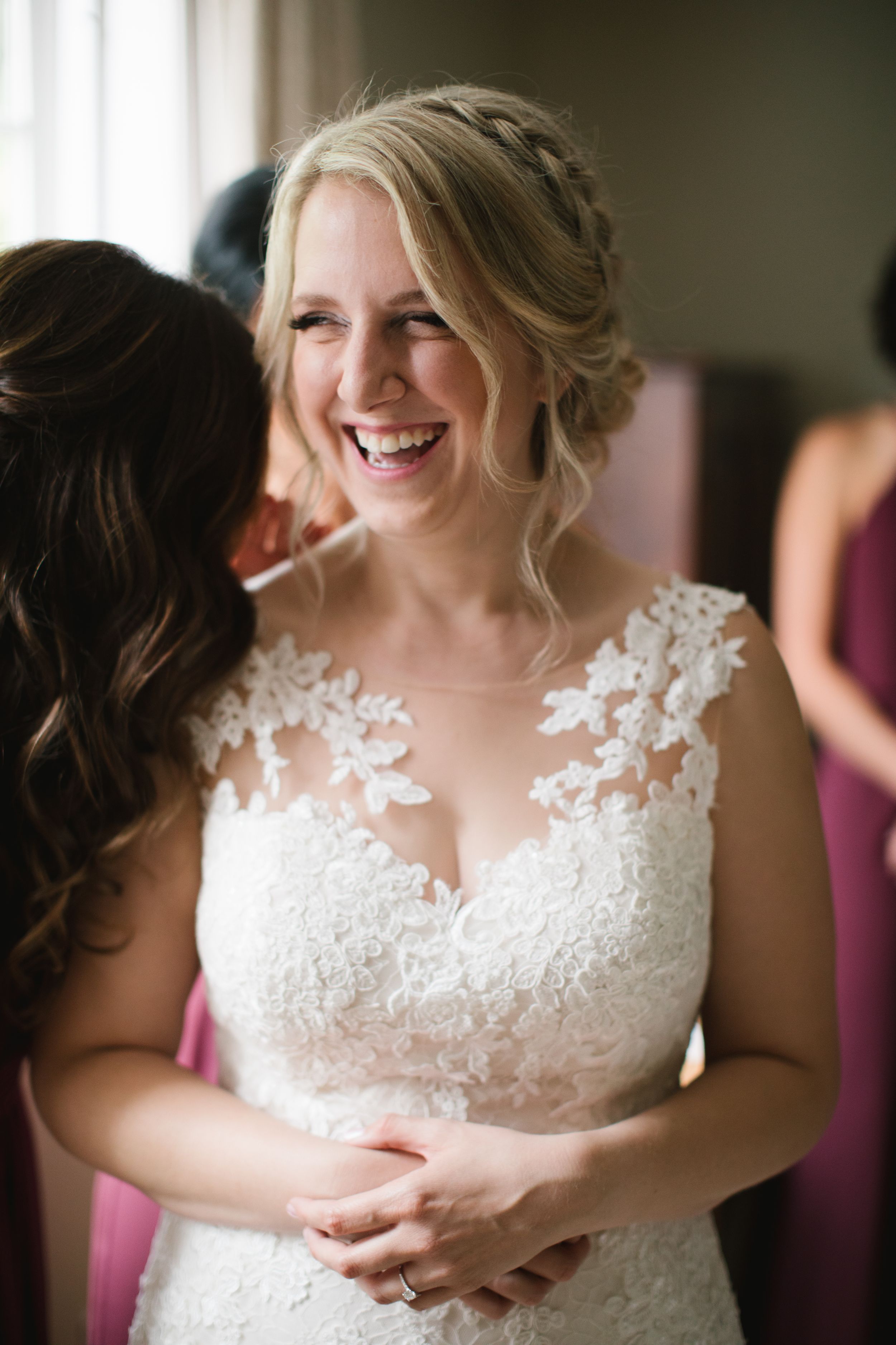 bride laughing as she is getting put into her wedding dress