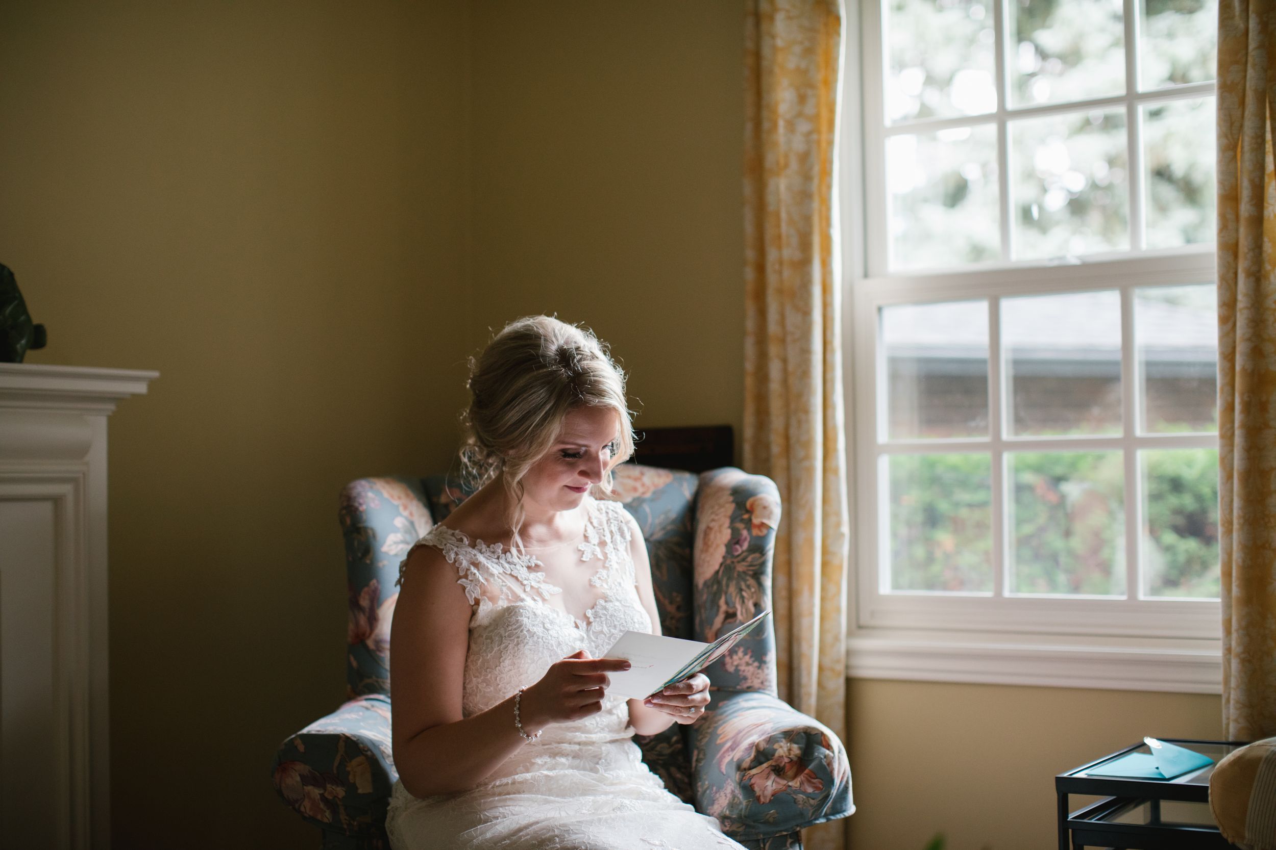 bride sitting in living room chair and opening her groom's letter
