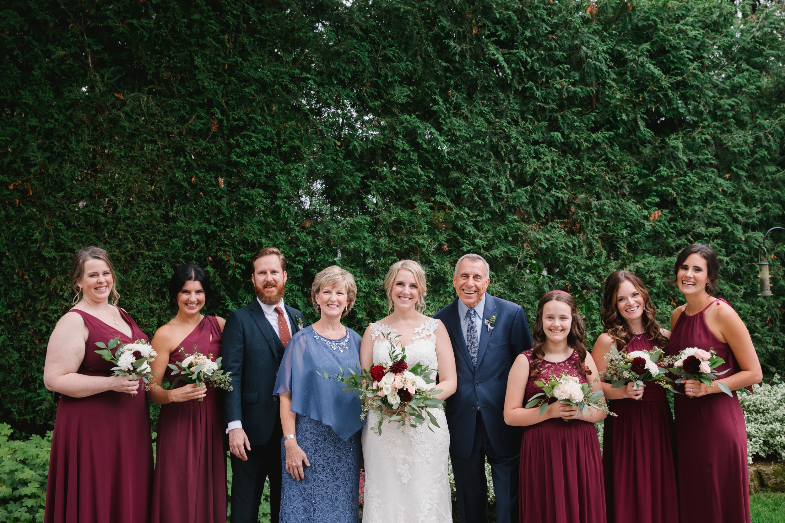 bridesmaids and parents of the bride with bride smiling in backyard