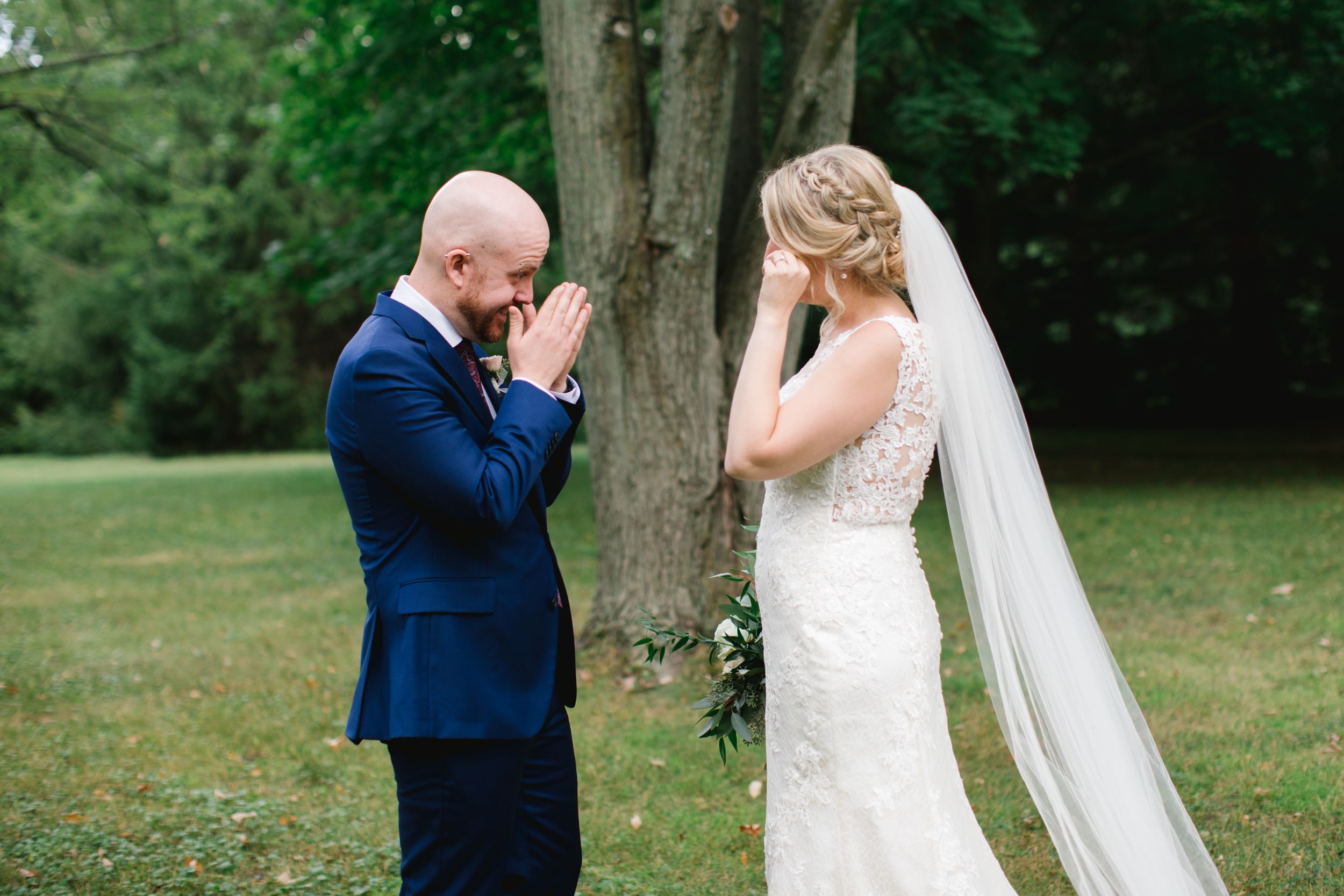 bride and groom wiping away tears after first look in park