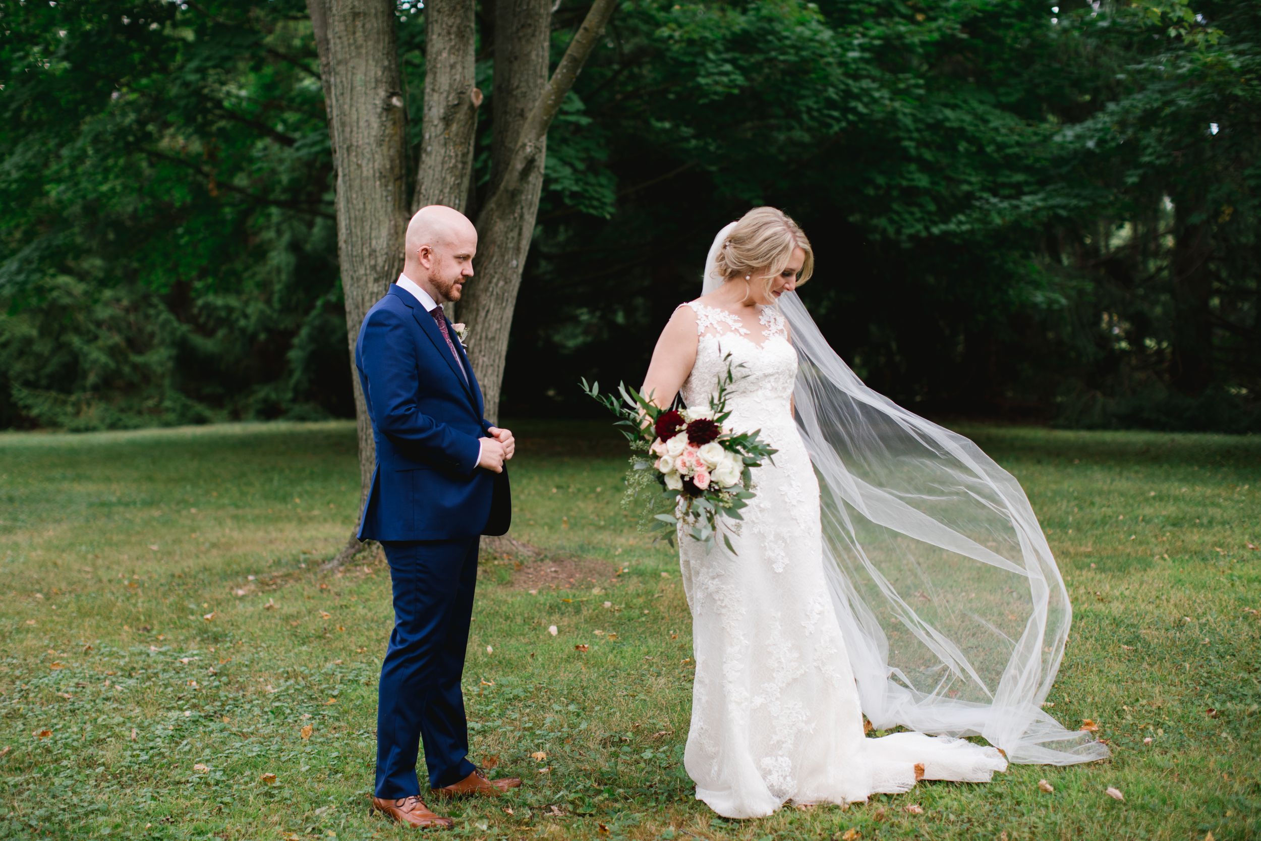 groom looking at bride throwing her veil in park