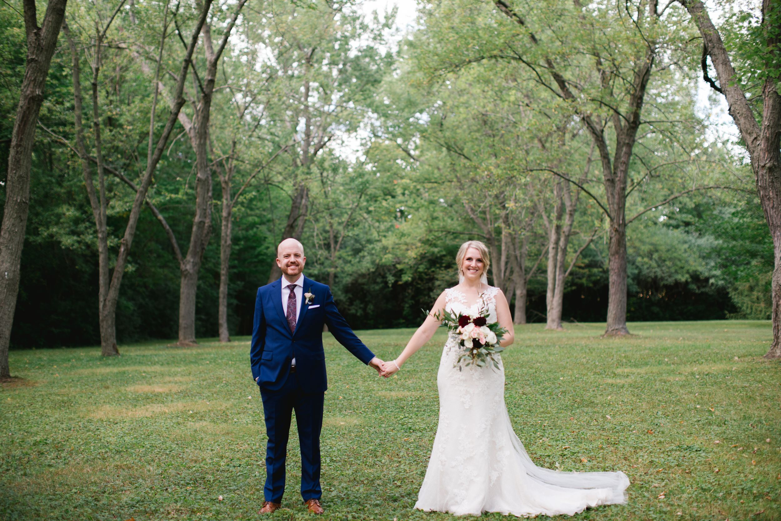 bride and groom holding hands and smiling in park toronto