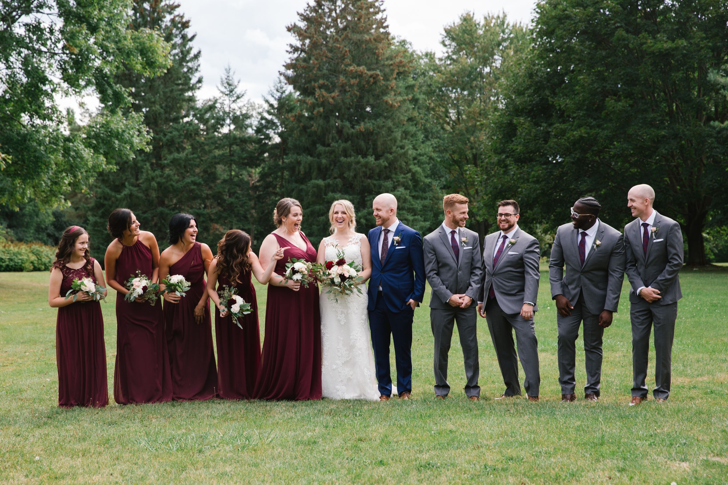 bridal party looking at each other and laughing in park