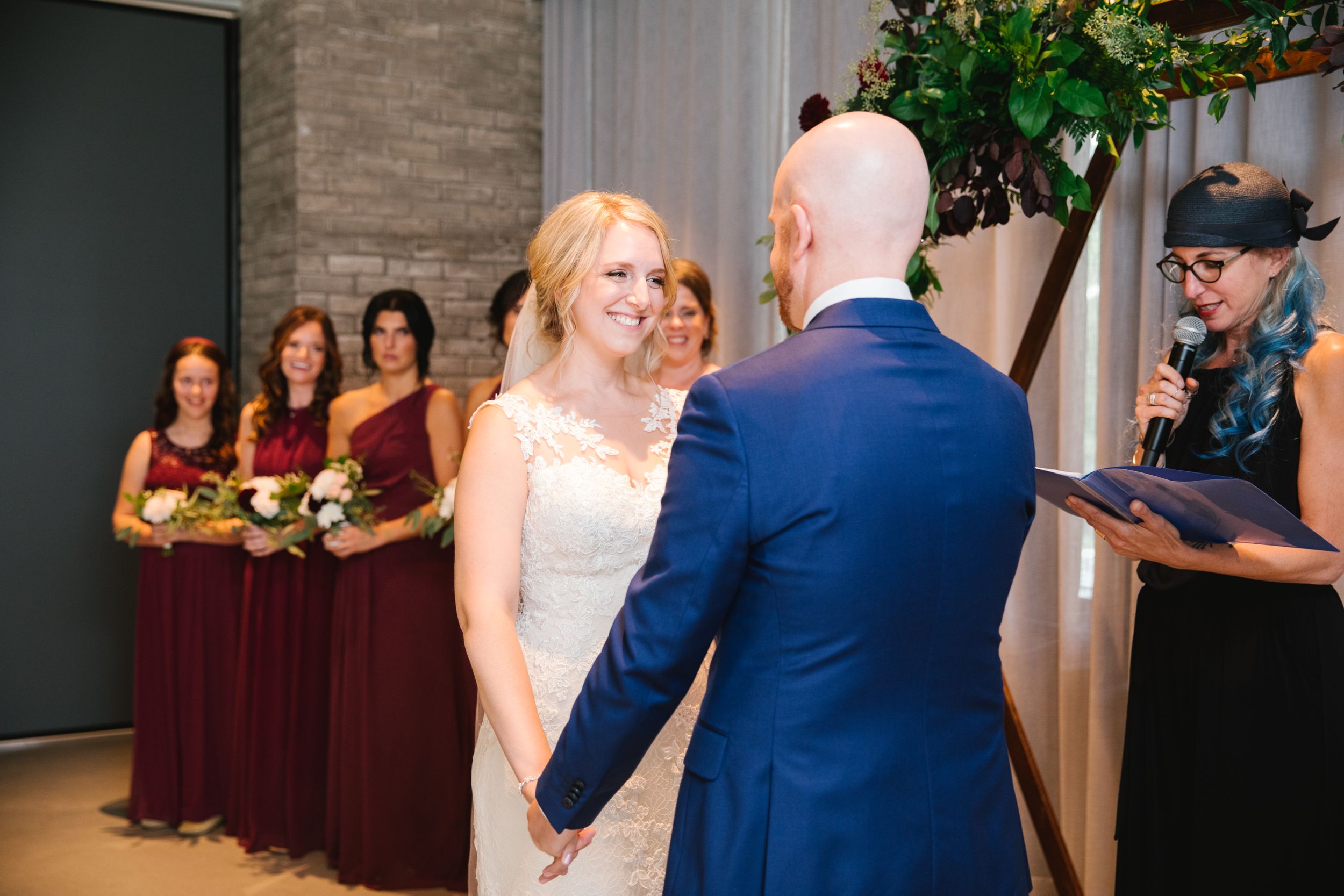 bride looking at groom and smiling with bridesmaids behind her during wedding ceremony