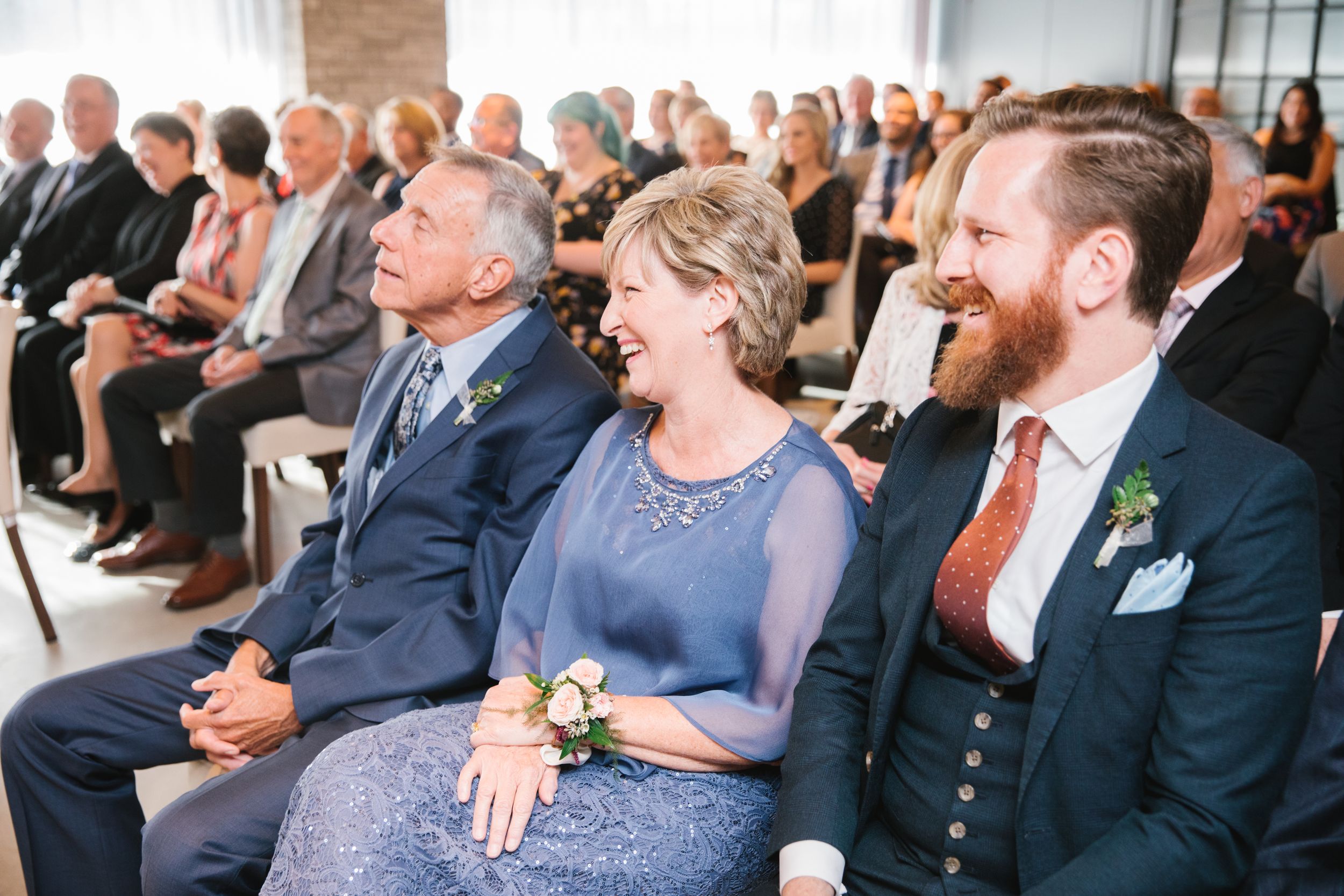mother of bride sitting in audience and laughing during ceremony
