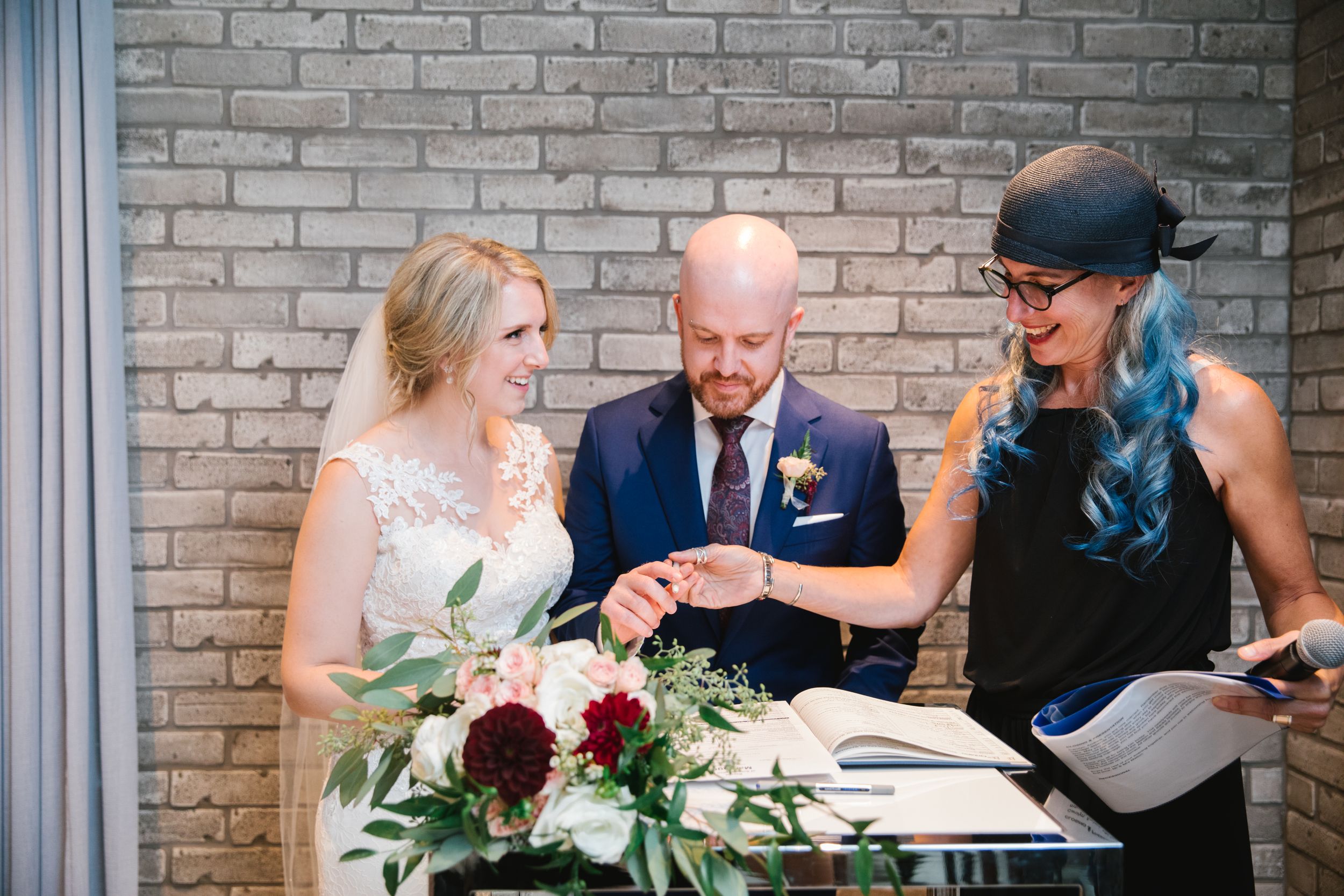 bride and groom and officiant with blue hair sign the wedding register toronto