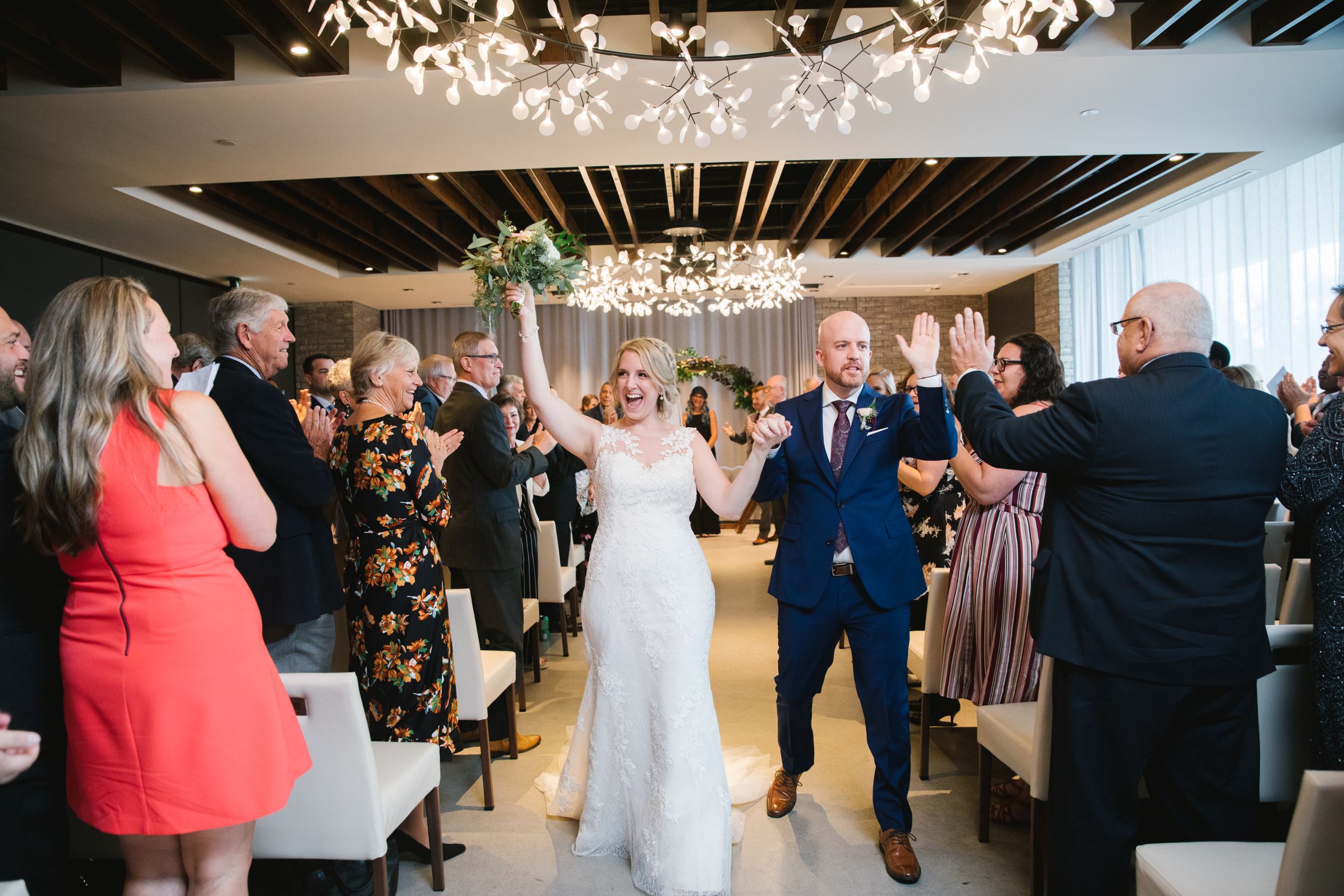 bride and groom celebrate walking down aisle with guests clapping indoors ceremony toronto
