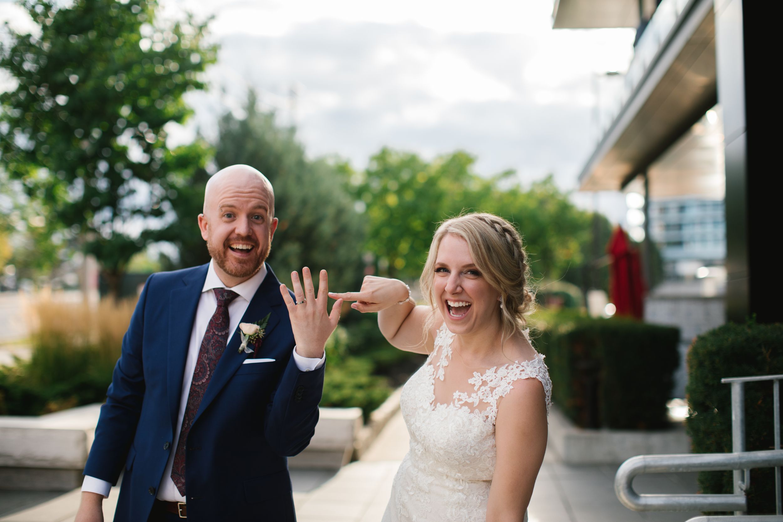 bride laughing and pointing at grooms ring finger