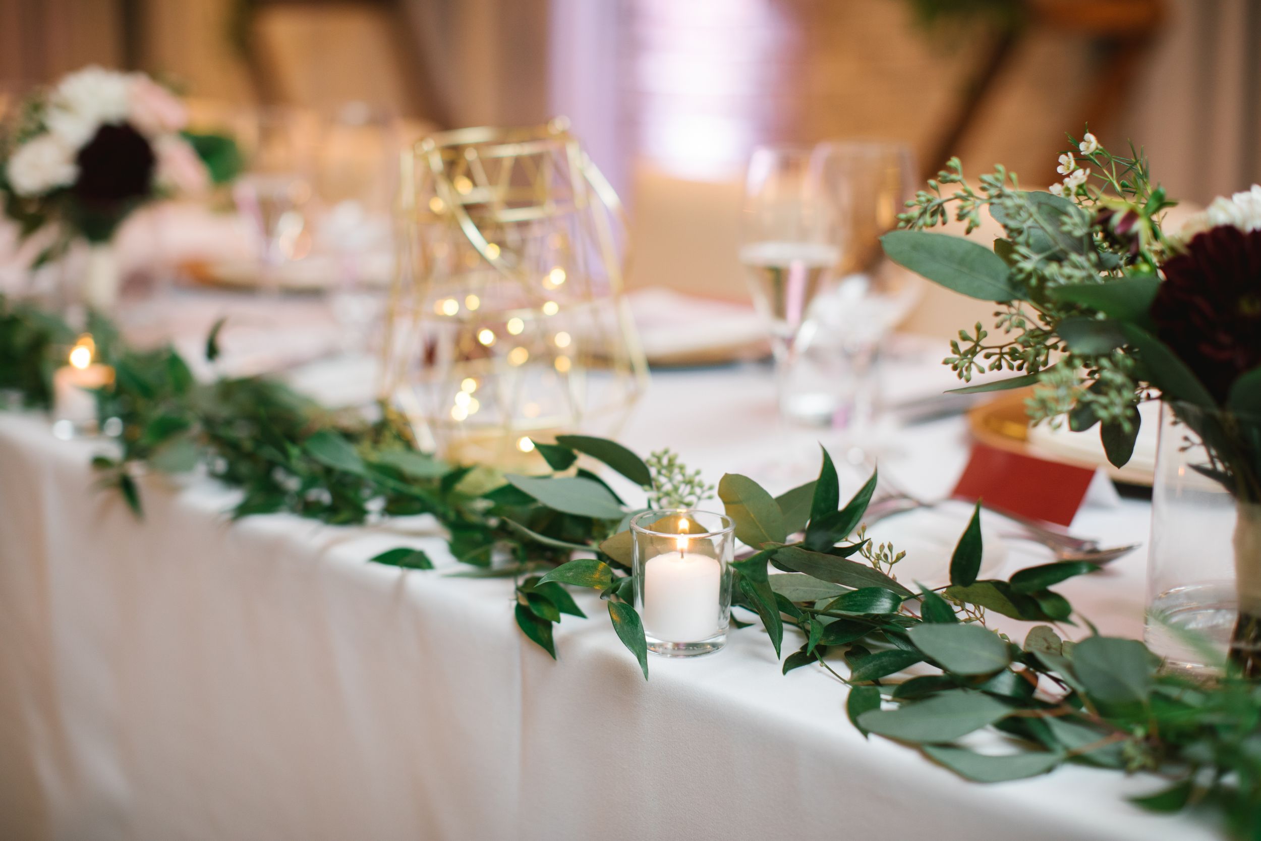 close up of wedding decor candle and greenery table runner head table