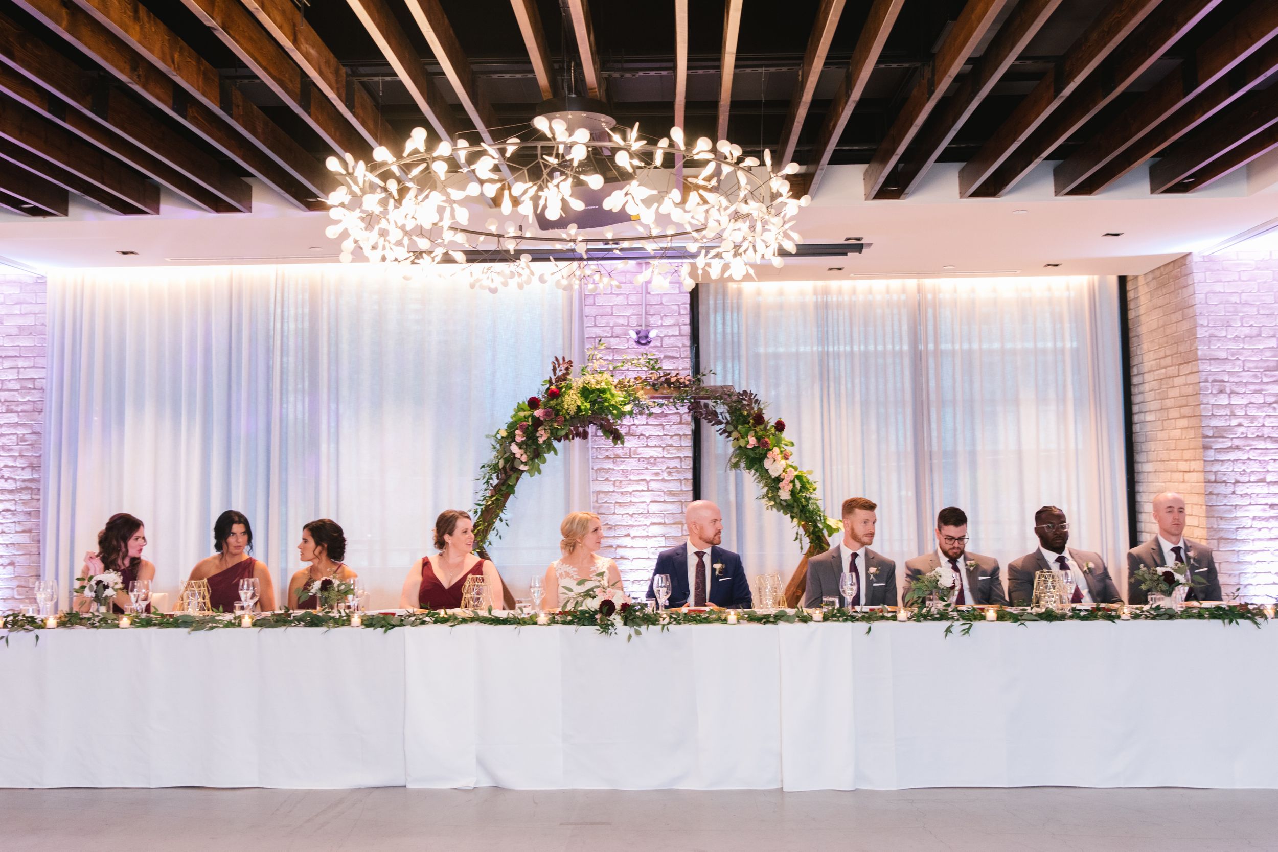 head table with floral arch behind them