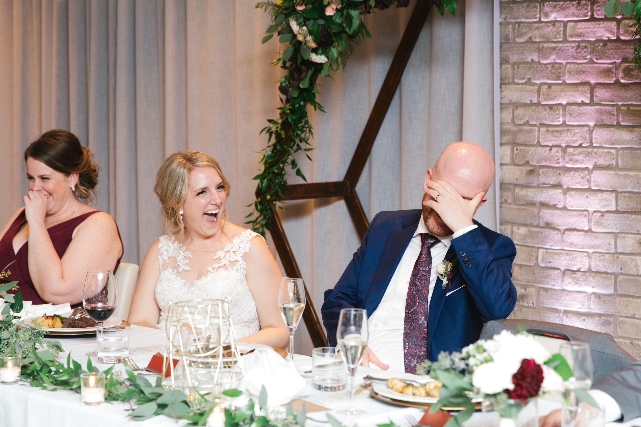 bride laughing and groom covering his face reception best man speech