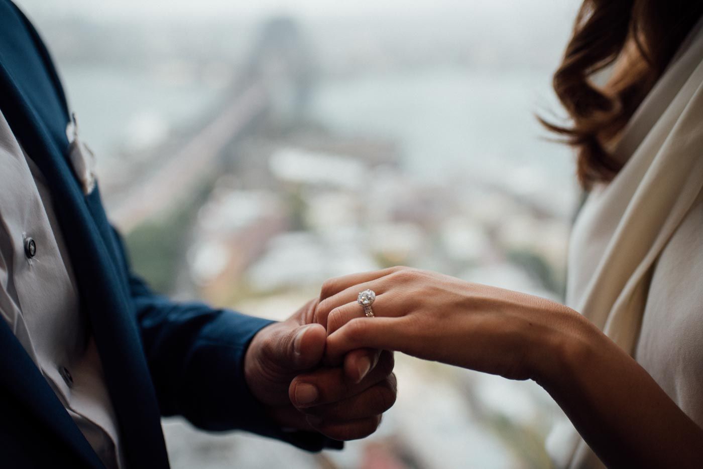 Groom holds the hand of Bride showing ring