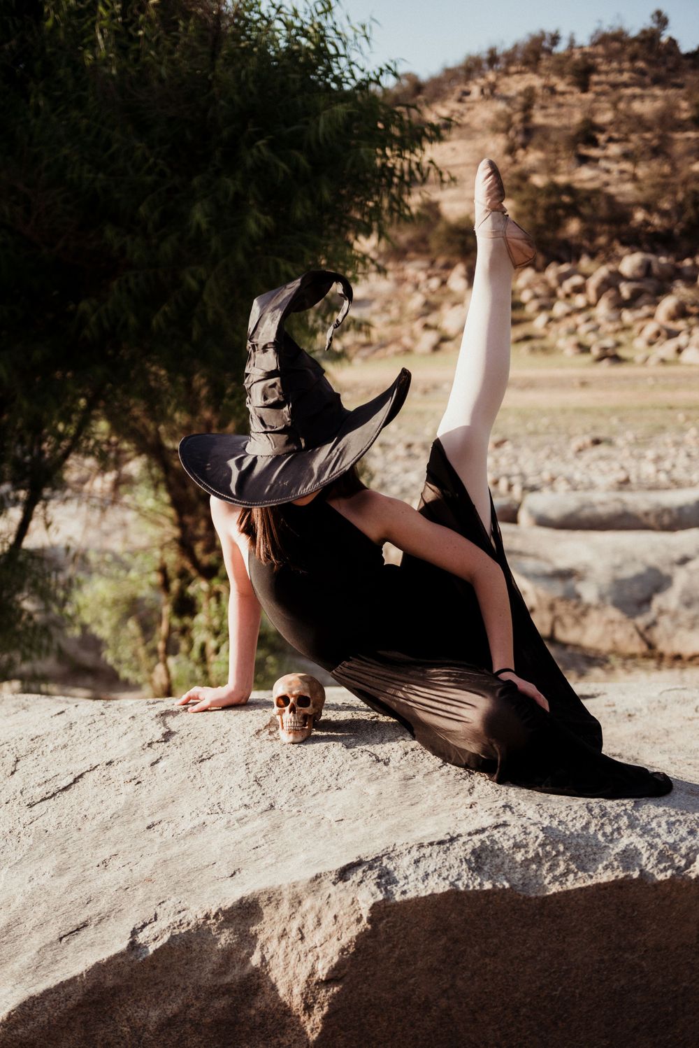 Girl dressed like a witch and posing on a boulder next to a skull for a Halloween photoshoot in Three Rivers California