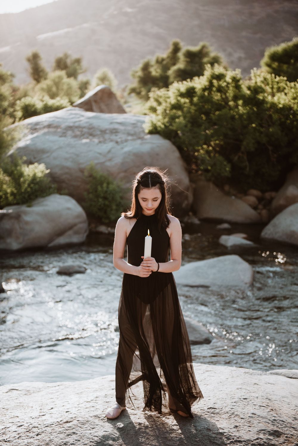 Girl posing with a lit candle during a river photography session for Halloween; Three Rivers, California