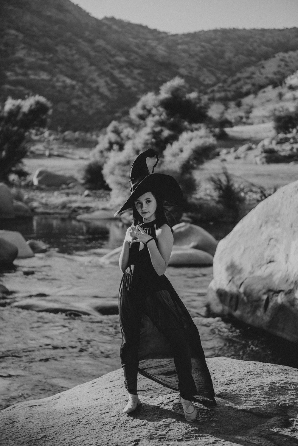 Girl posing in a witch's hat in front of the river; Halloween photoshoot in Three Rivers, California