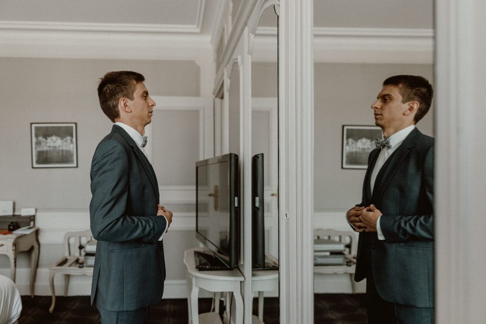 groom facing the mirror in his suit before wedding at l'hotel de la reine Nancy