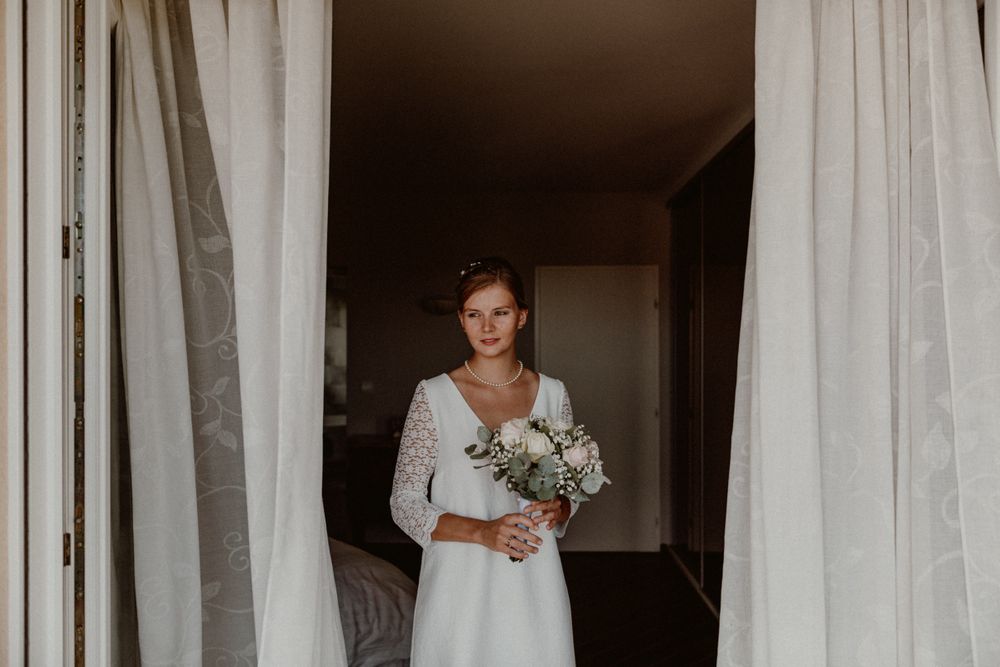 bride getting ready in front of a window with curtains