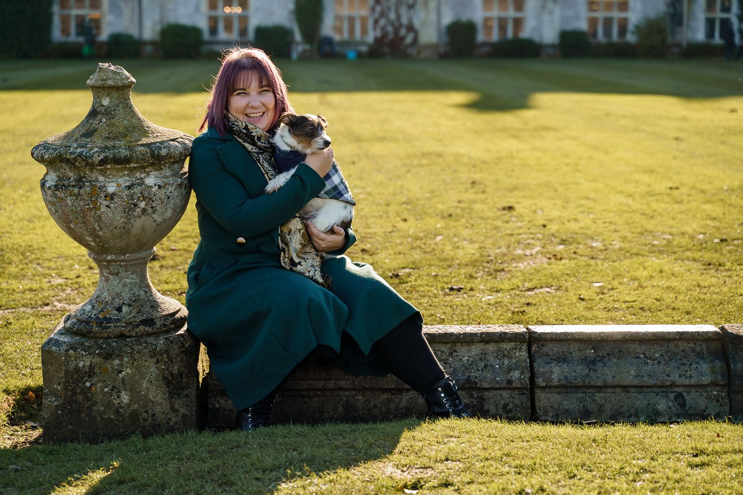 Dog-friendly wedding photographer Katherine hugs her Jack Russell in a walled garden. Top 10 dog-friendly wedding tips.