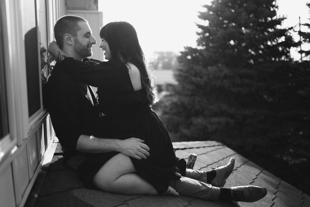 couple-sitting-on-rooftop-looking-at-each-other-winterset-iowa-raelyn-ramey-photography