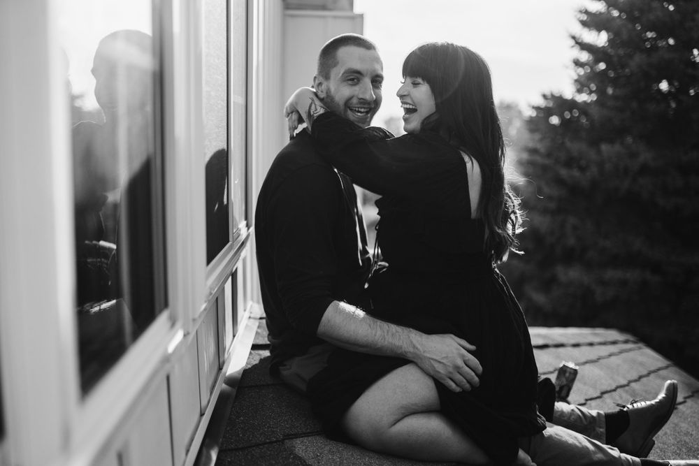 couple-sitting-on-rooftop-laughing-cuddling-winterset-iowa-raelyn-ramey-photography
