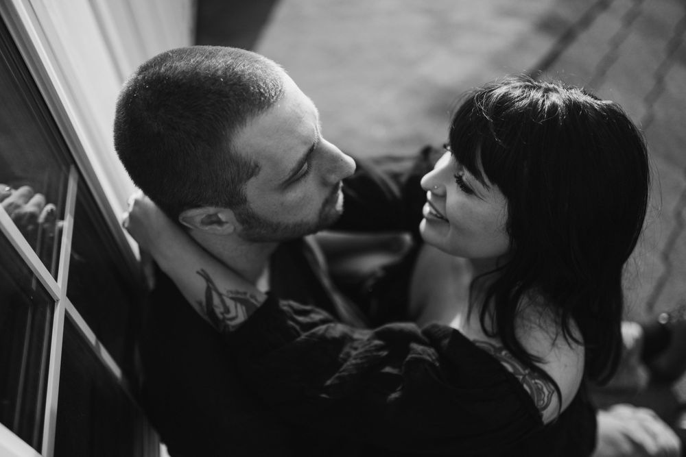 fiance-sitting-on-fiance-lap-looking-at-each-other-on-rooftop-winterset-iowa-raelyn-ramey-photography