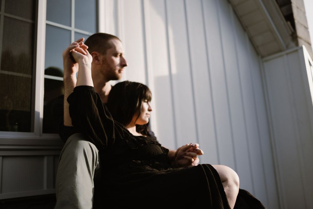 couple-watching-sunset-on-house-rooftop-holding-hands-winterset-iowa-raelyn-ramey-photography