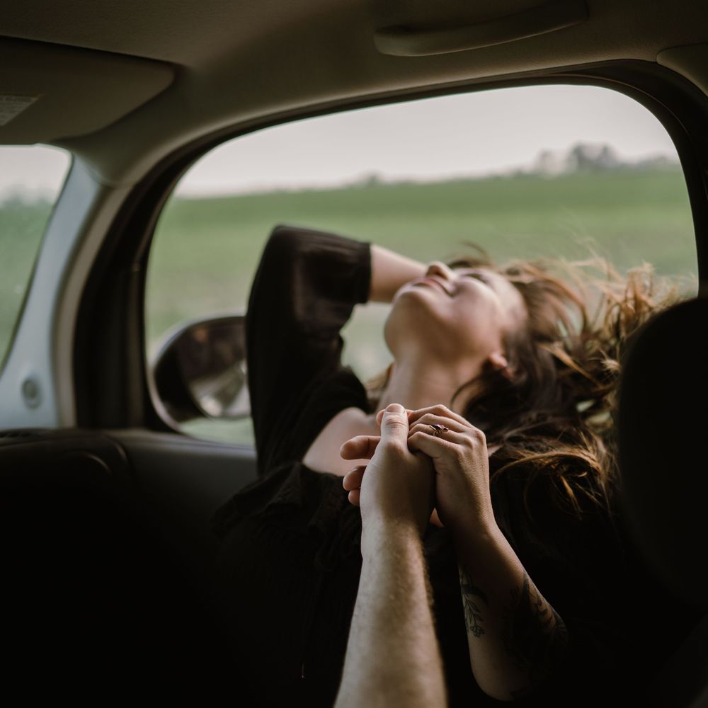 couple-roadtrip-woman-hanging-her-hair-out-window-winterset-iowa-raelyn-ramey-photography