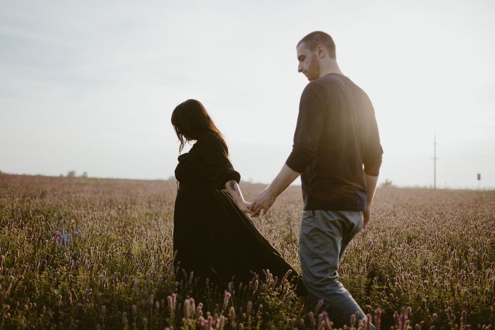 couple-walking-in-flower-field-winterset-iowa-raelyn-ramey-photography