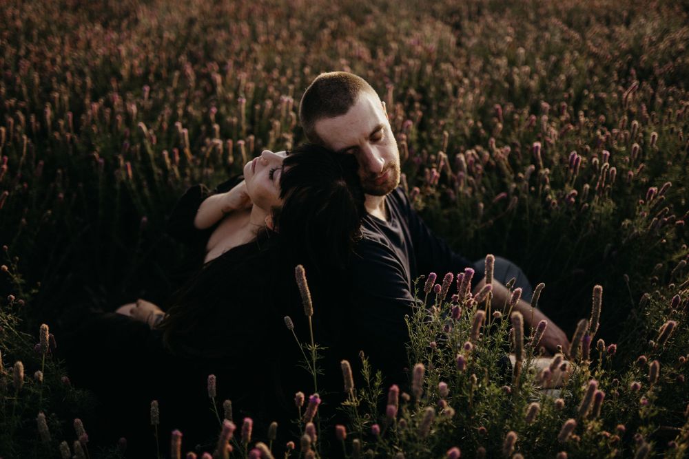 couple-sitting-in-flower-field-laying-back-on-each-other-winterset-iowa-raelyn-ramey-photography