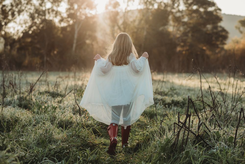 a girl in a communion dress and wellies running