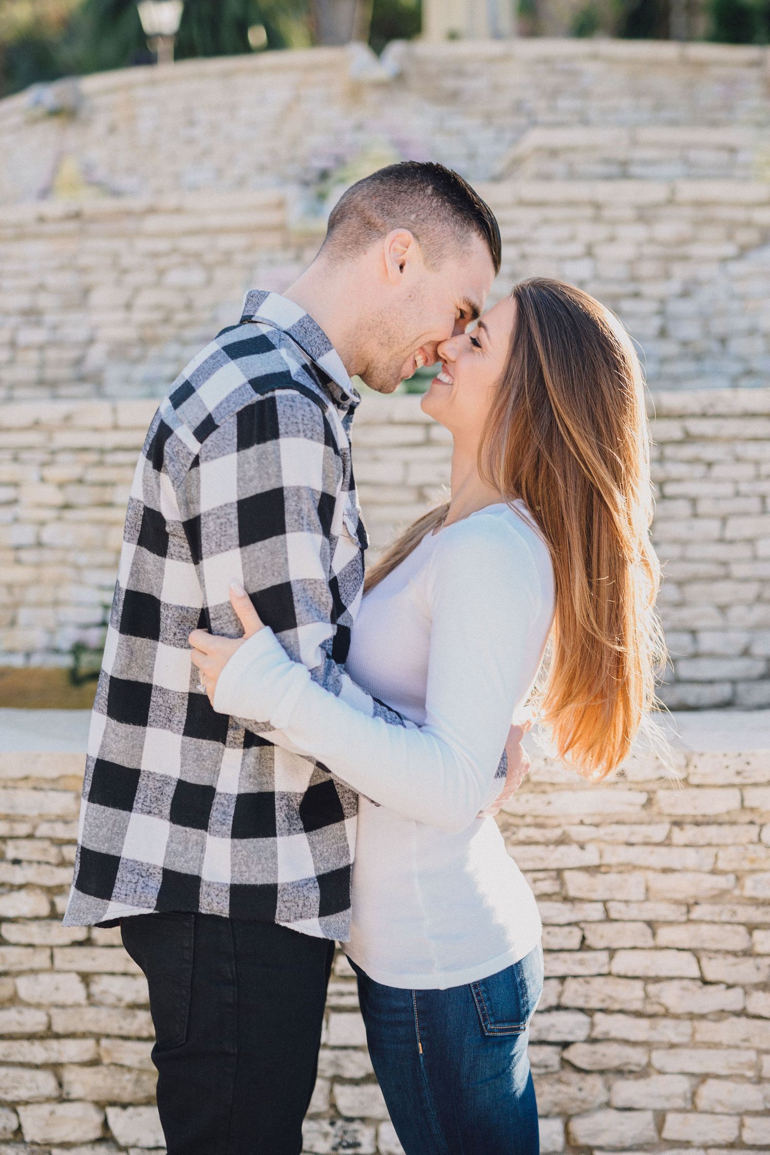 couple kiss in front of brick fountain