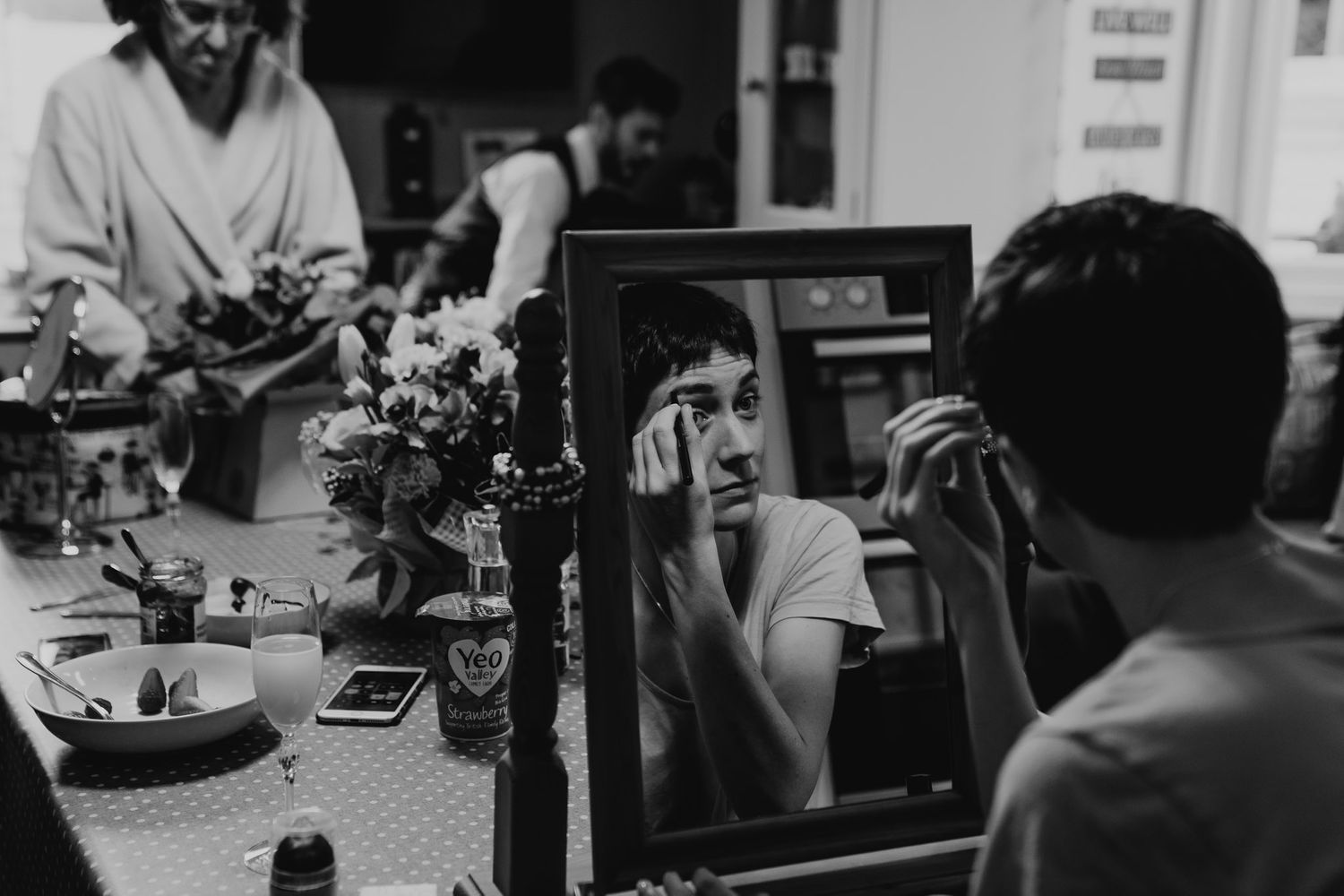 Bride does her make up at the kitchen table surrounded by her family.