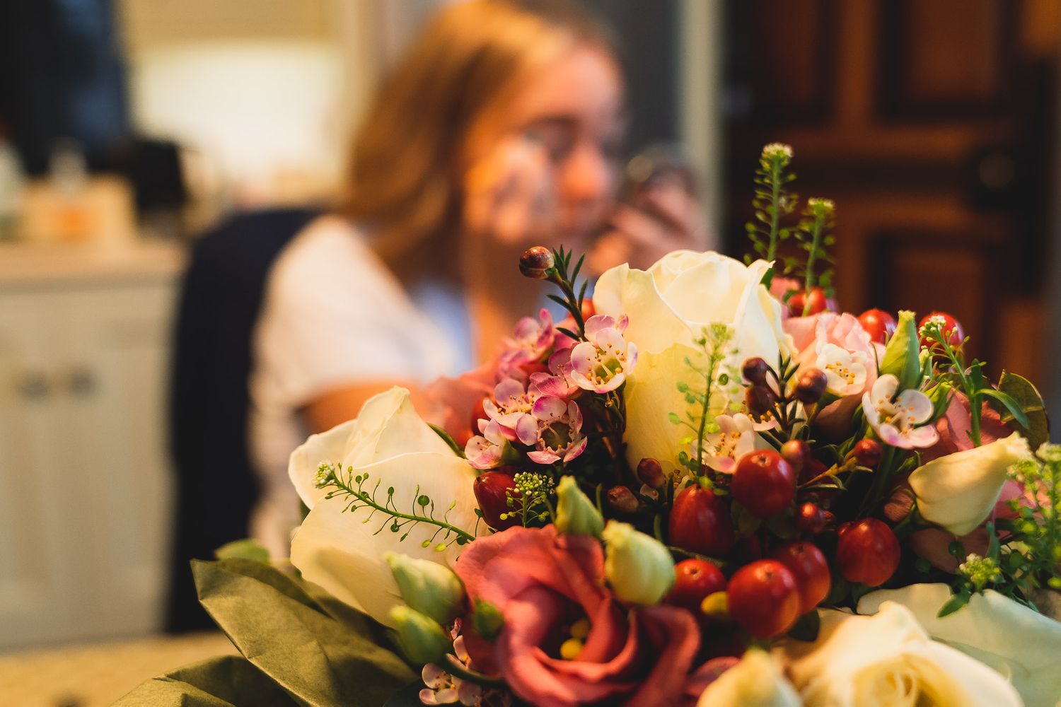 Wedding bouquet is in focus in the foreground, bridesmaid does her makeup in the background. Salisbury wedding prep.