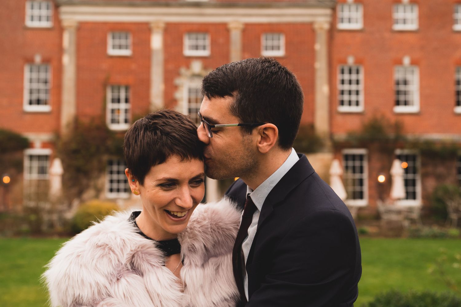 Groom kisses his new wife on the temple outside their wedding venue, 10 Castle Street in Dorset.