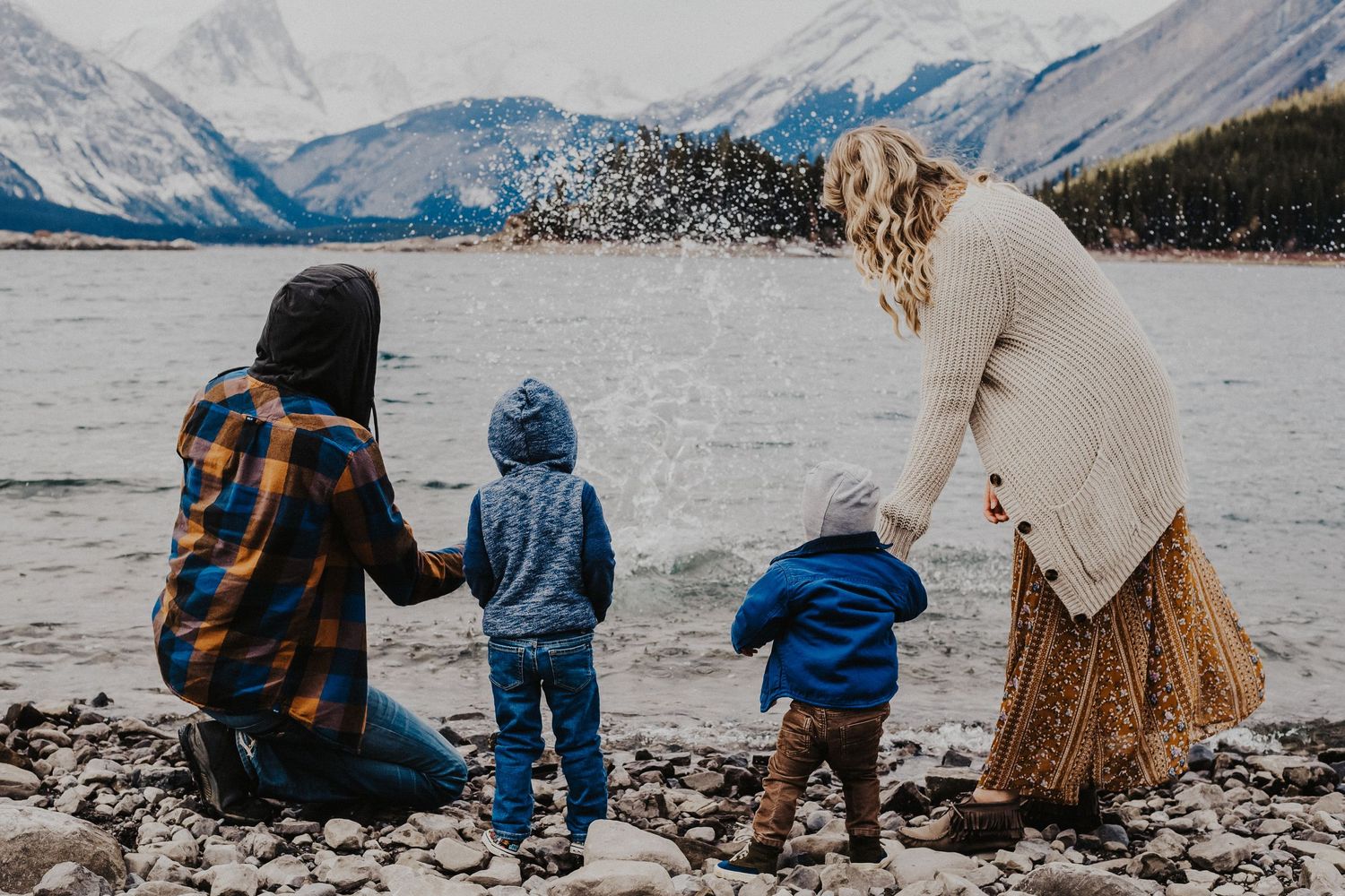 family of four throw rocks into upper lake kananaskis