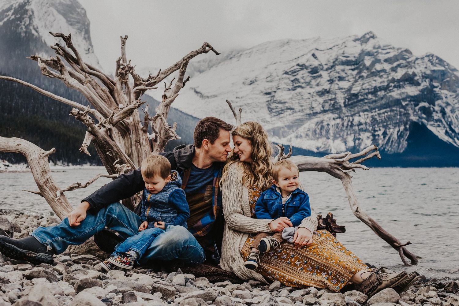 mom and dad touch noses while each holding a son