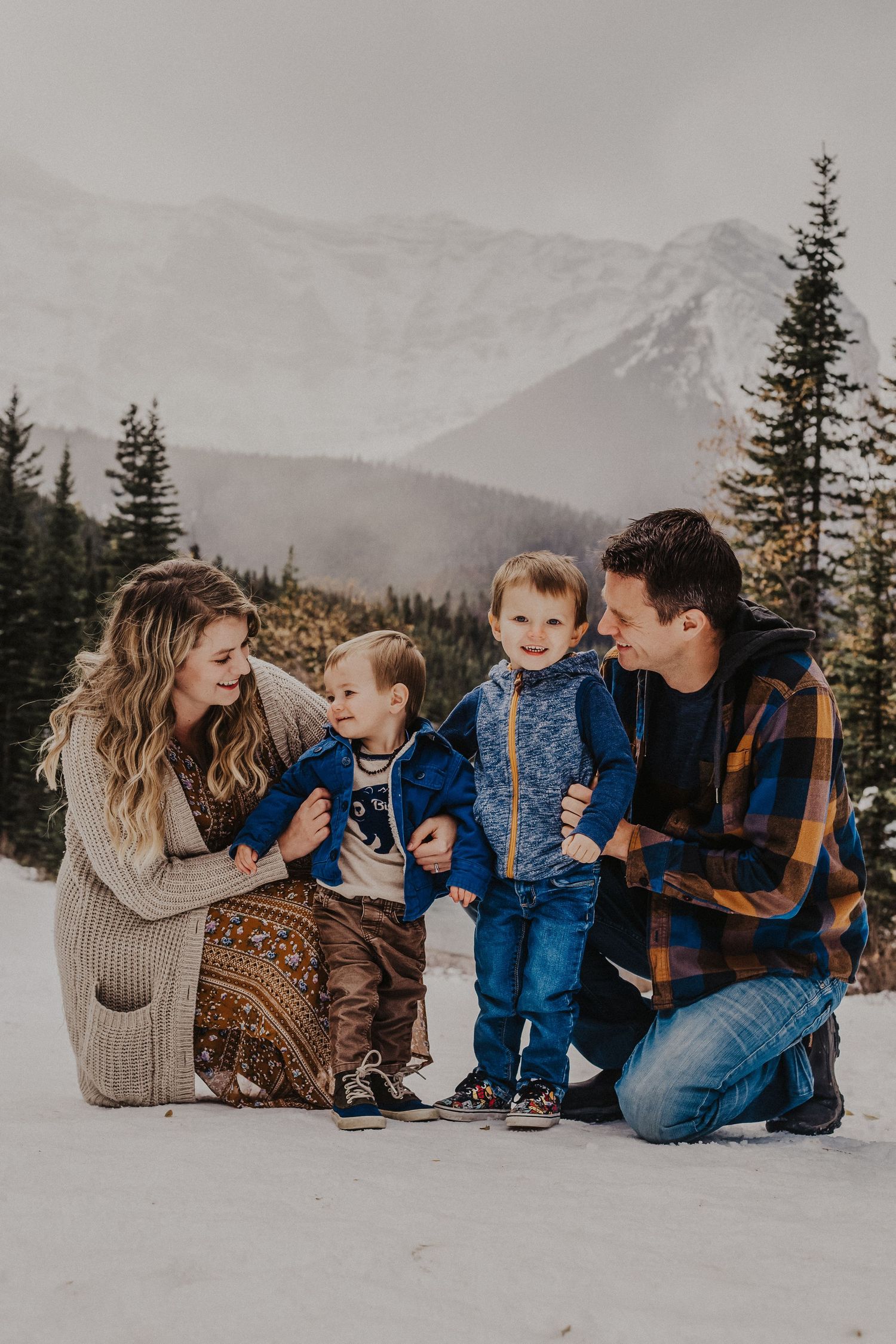 family cuddles and laughs in front of mountains